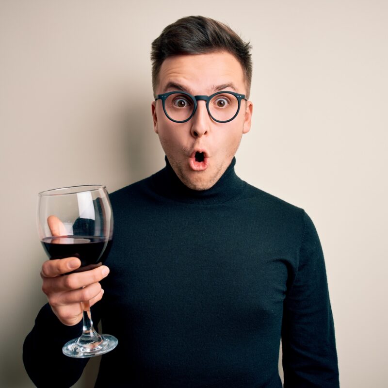 Young handsome caucasian man drinking an alcoholic glass of red wine over isolated background scared in shock with a surprise face, afraid and excited with fear expression Young handsome caucasian man drinking an alcoholic glass of red wine over isolated background scared in shock with a surprise face, afraid and excited with fear expression